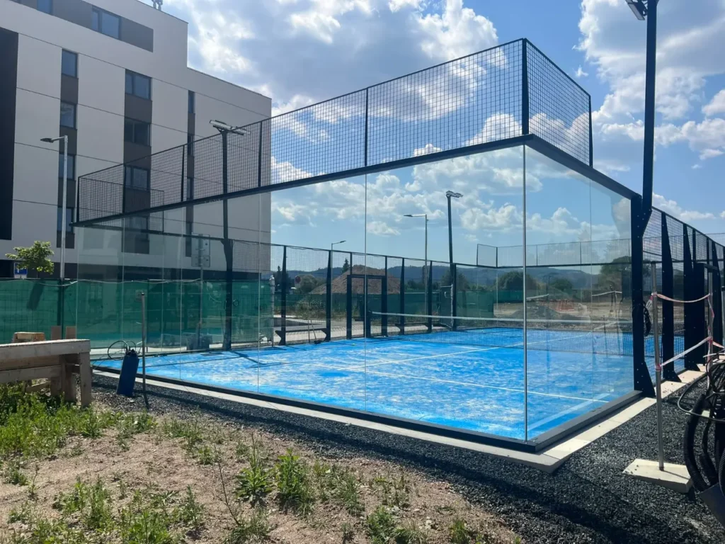 Vonkajší super panoramatický padelový kurt so sklenenými stenami a modrým povrchom v Poprade