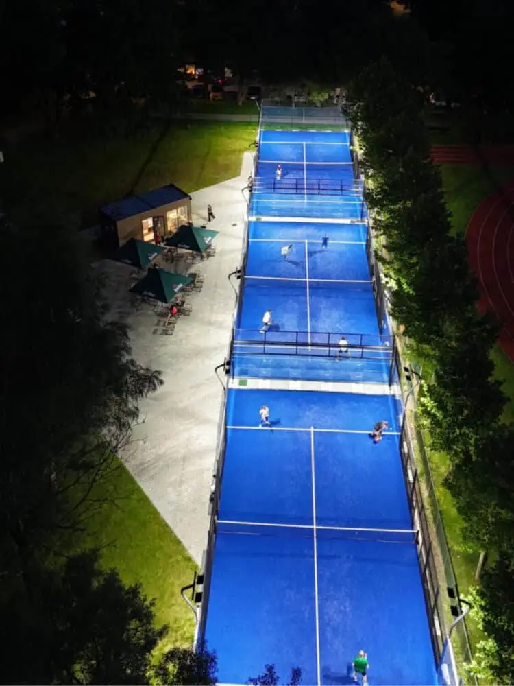 Tri osvetlené padelové kurty Padel Point v Žiline zhora, vedľa nich altánky a zázemie klubu